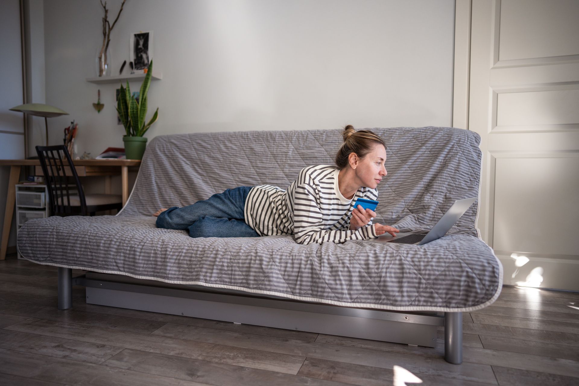 A woman is laying on a couch using a laptop computer.