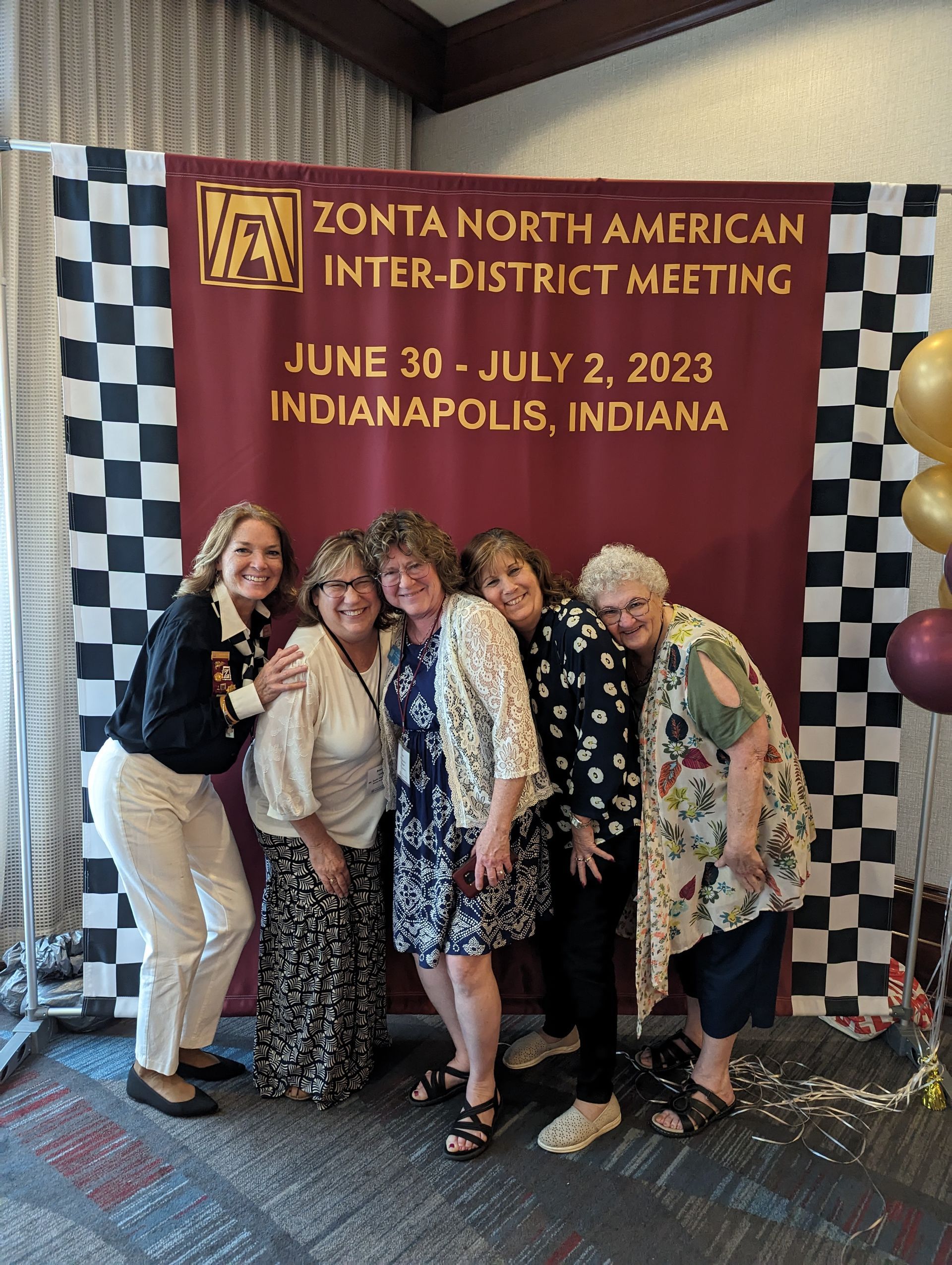 Group of women at a Zonta North American meeting in Indianapolis. Sign with event details.