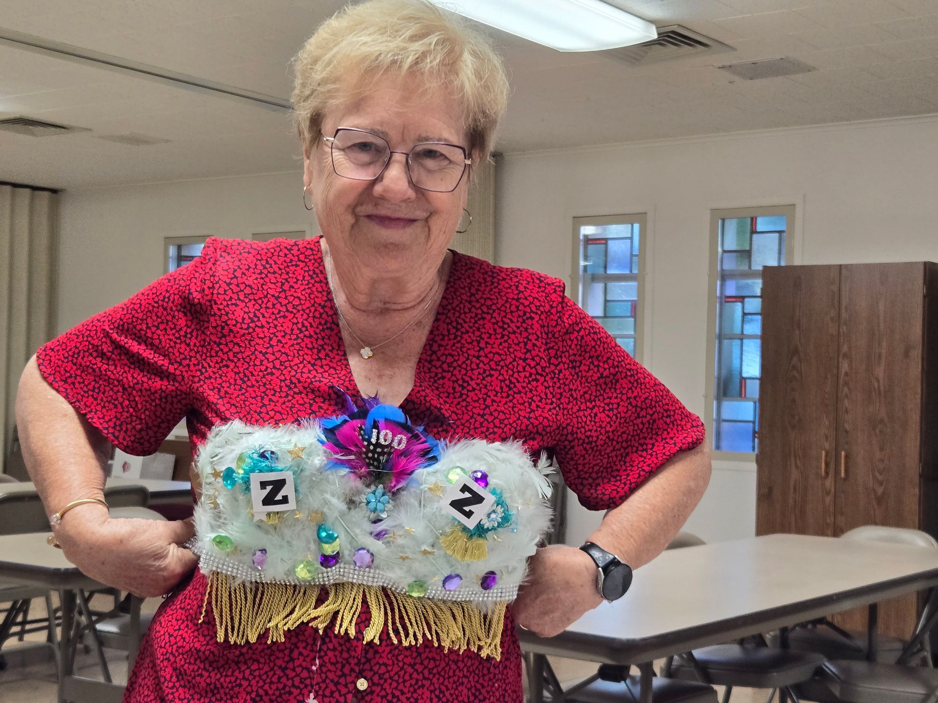 Woman in a red shirt wearing a decorated vest with the letter 