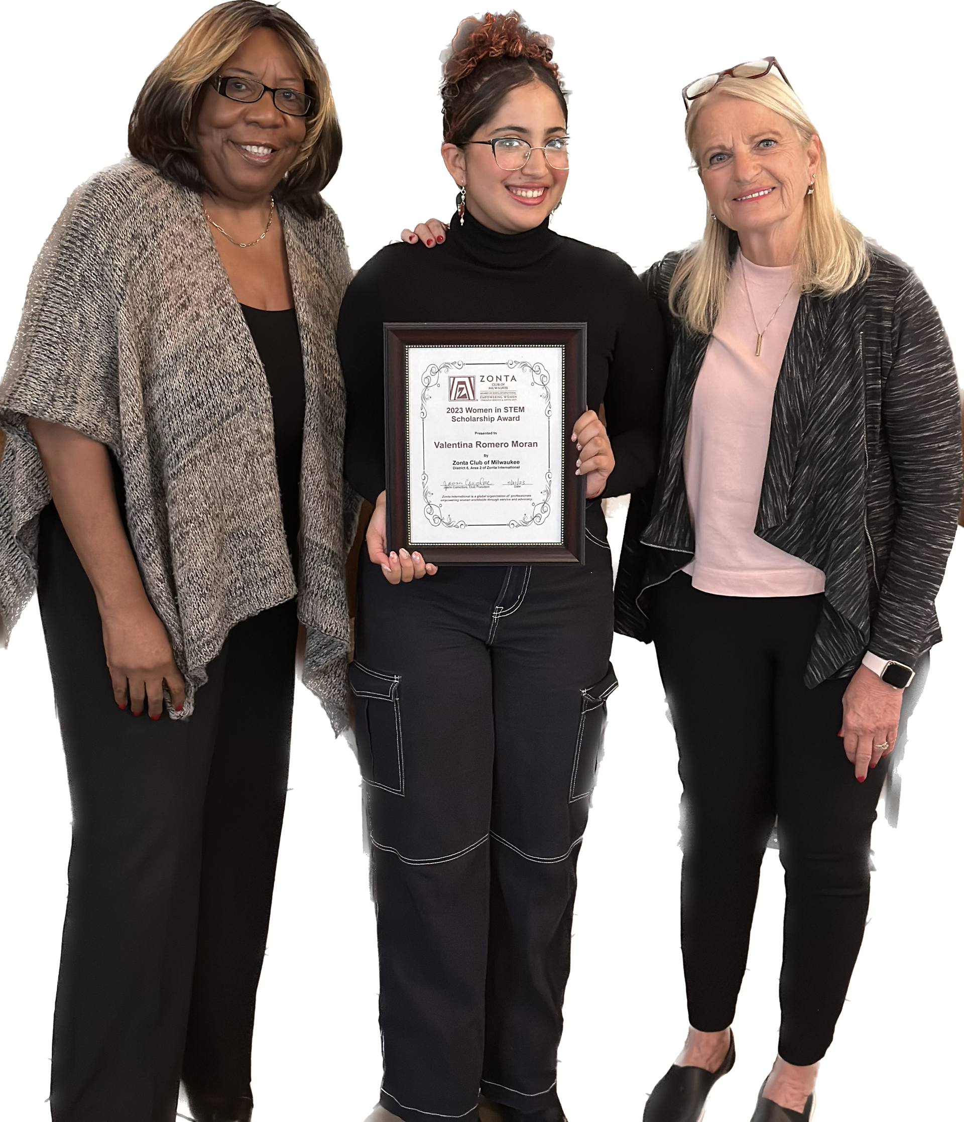 Three women smiling, holding an award. Two on either side of a woman in black, holding the framed award.