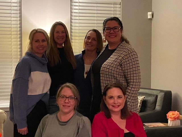 Group of six women posing together indoors.
