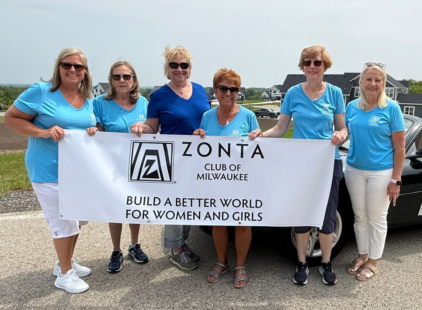 Six women holding a banner that says