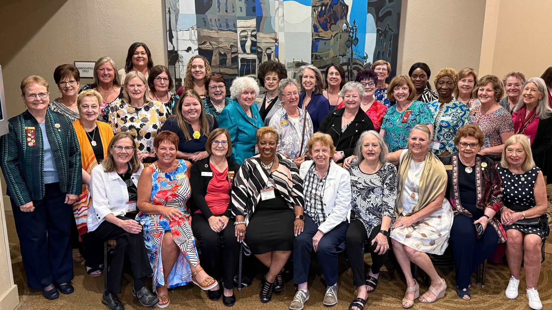 Group photo of diverse women smiling in a room with artwork on the wall.
