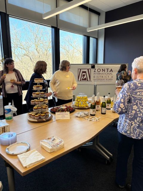 People at a catered event with food and drinks; Zonta logo visible in the background.