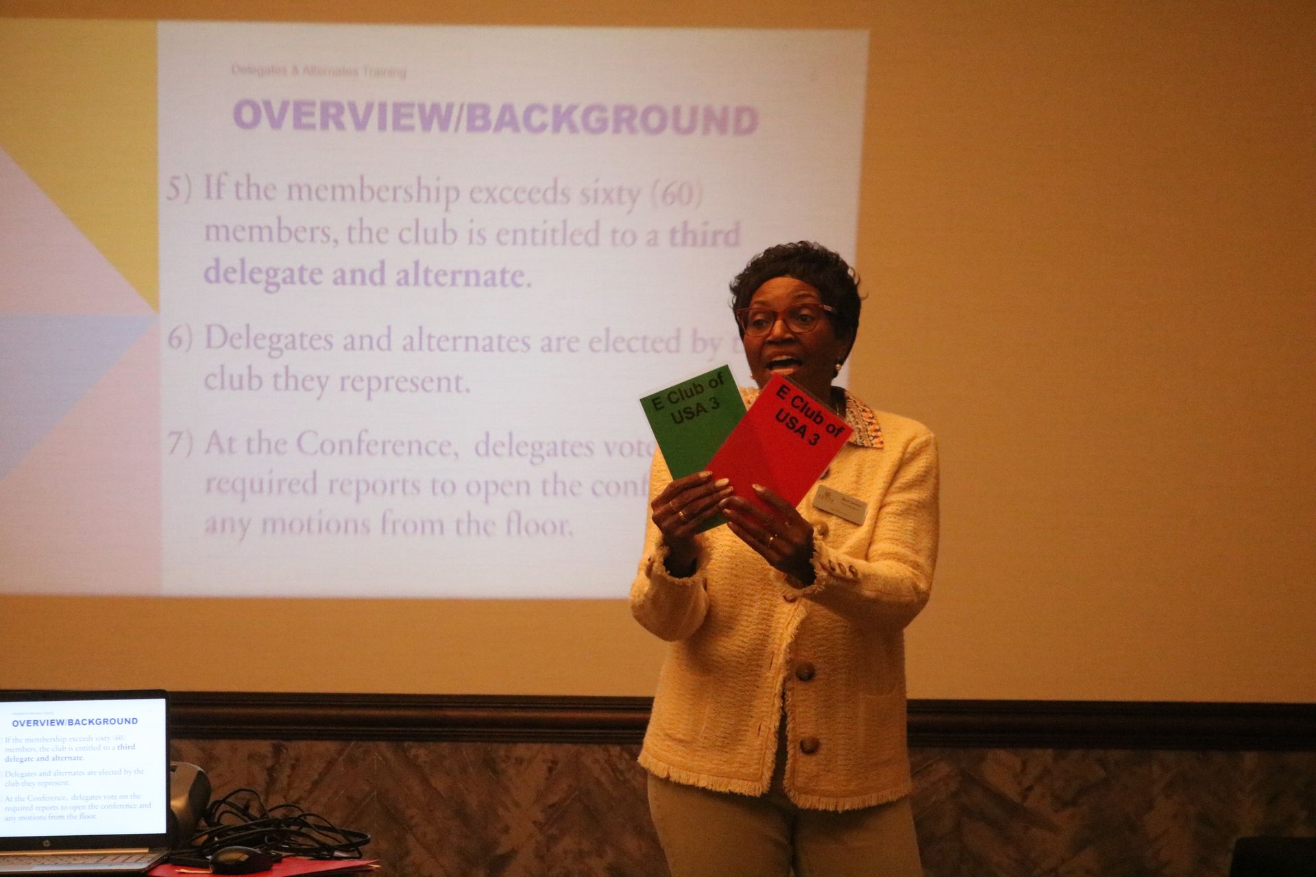 Woman holding green and red cards in front of a projection screen with text.