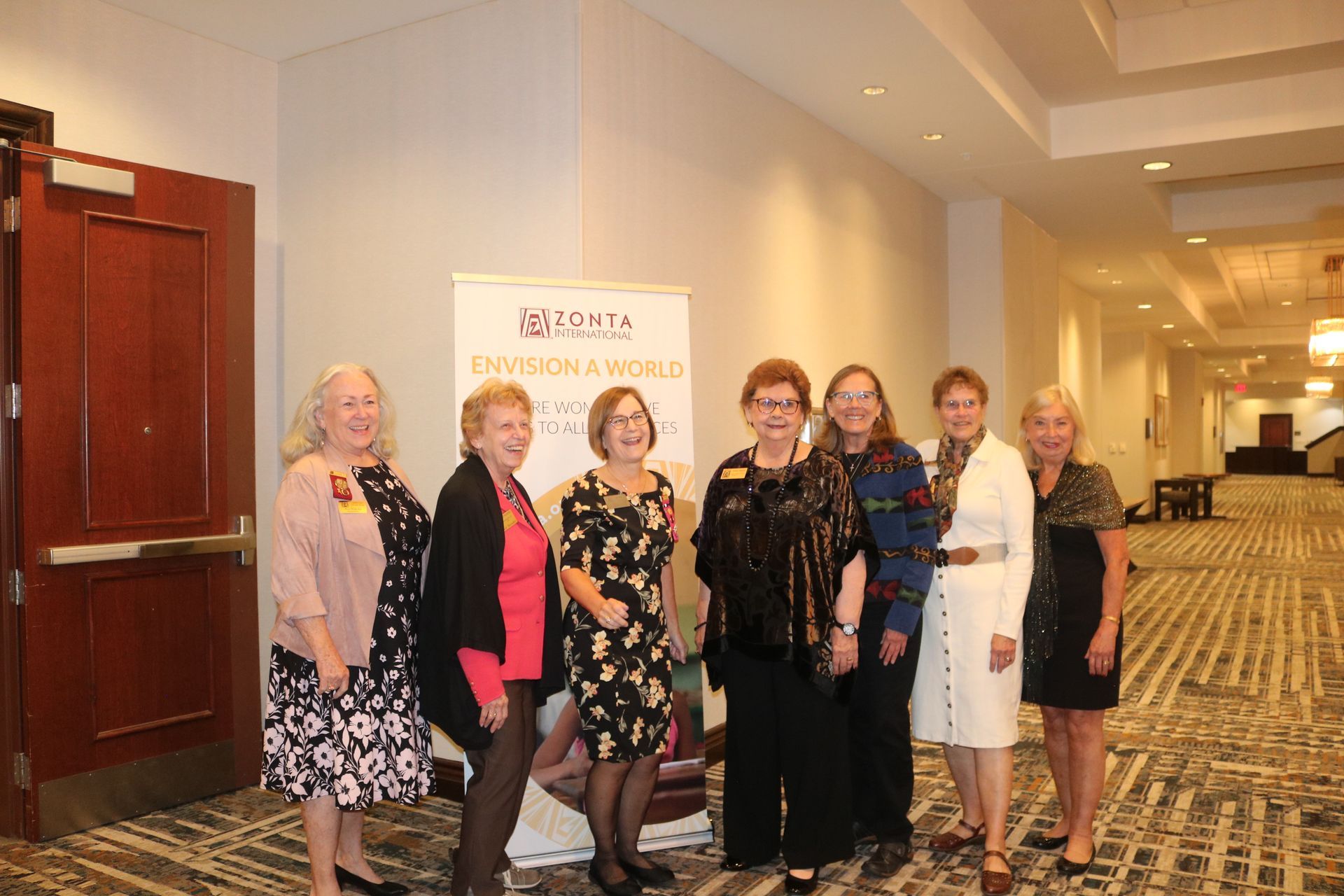 Group of women posing near a banner that says 
