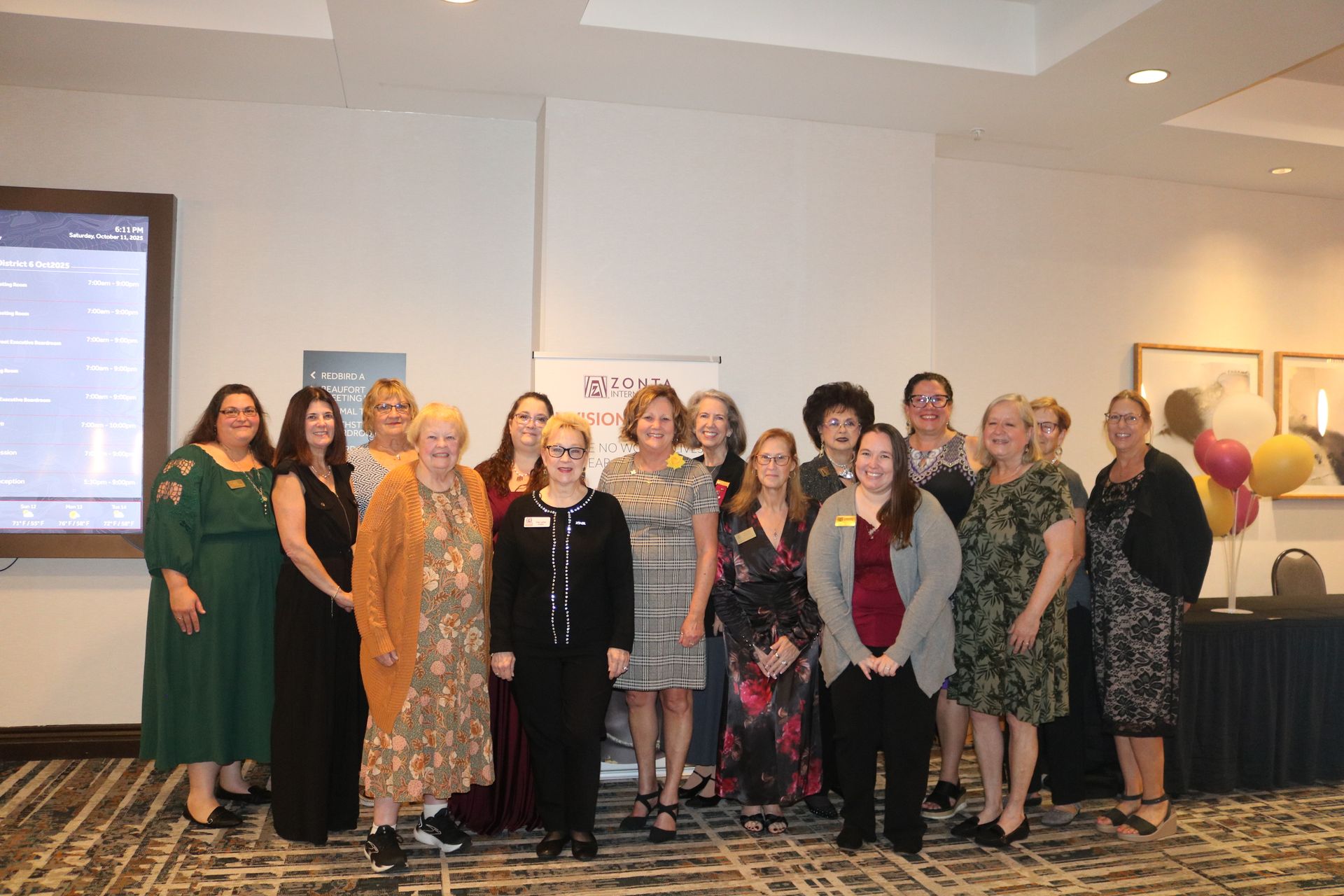 Group of women smiling, posing for a photo indoors, possibly an event or conference.
