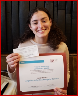 Woman holding an award and a check, smiling. She is seated indoors.