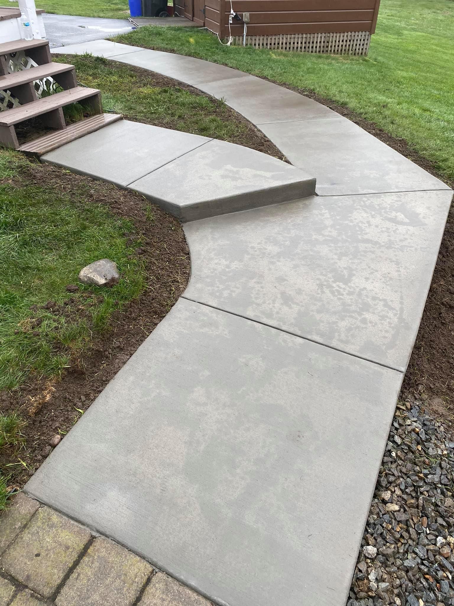 A concrete walkway with steps leading up to a house.