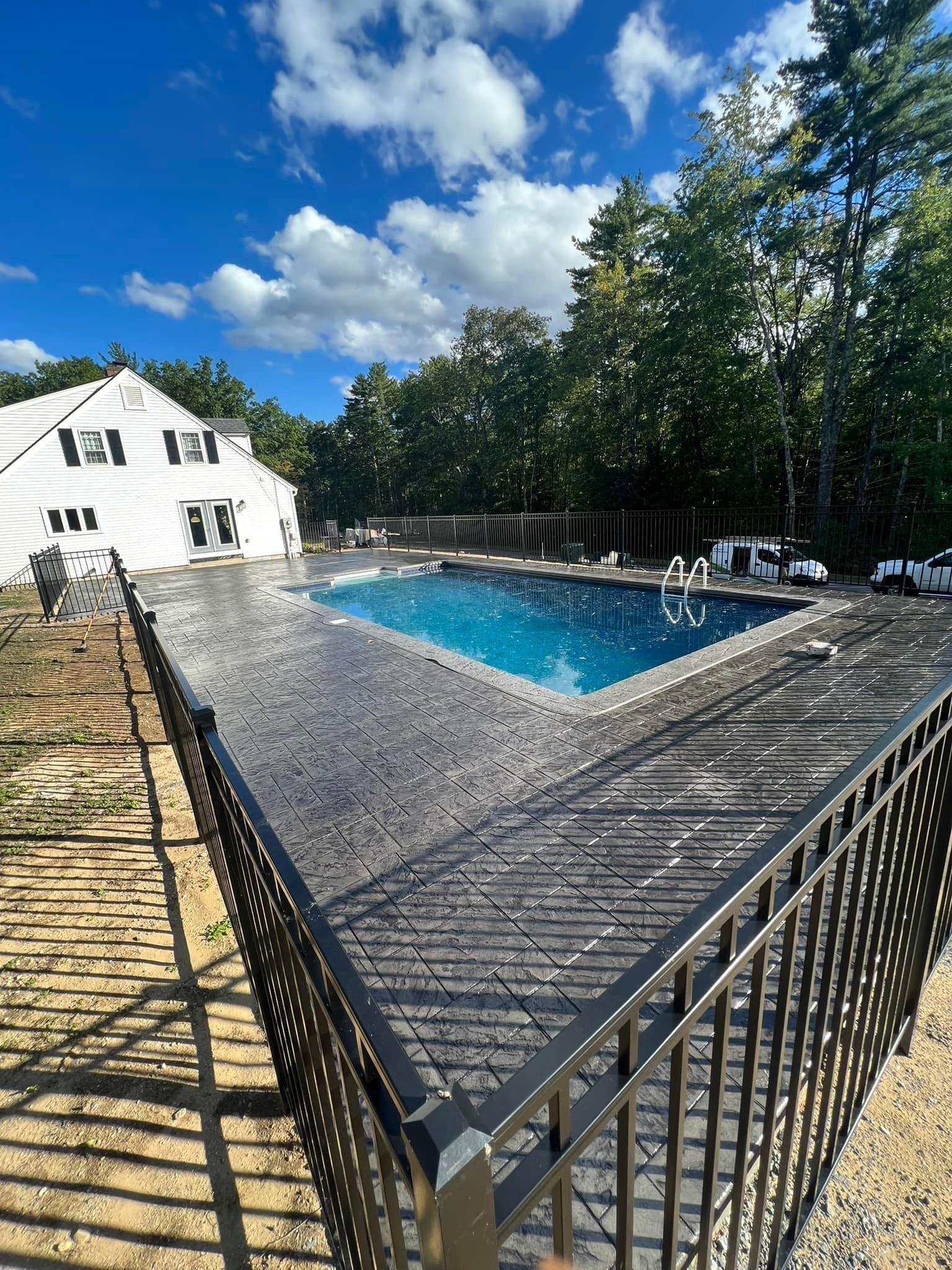 A large swimming pool is surrounded by a metal fence.