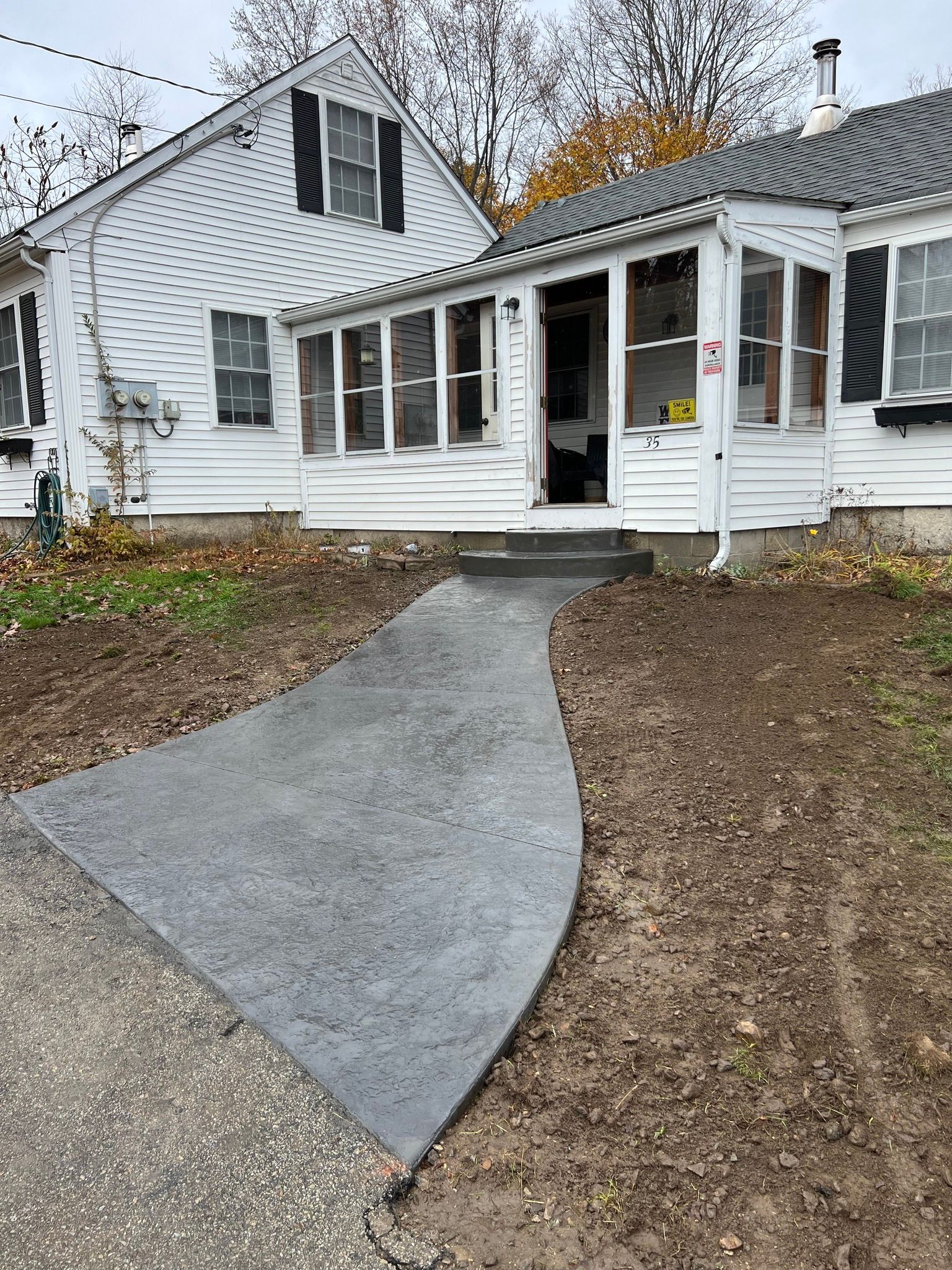 A white house with a concrete walkway leading to the front door.