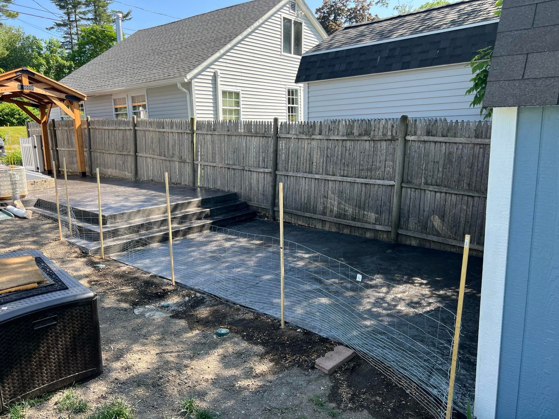 A fence surrounds a patio area in front of a house.