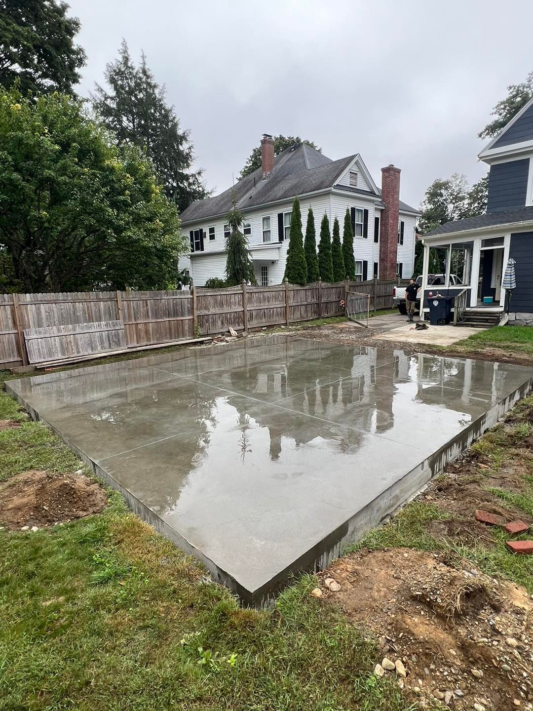 A large concrete slab is sitting in the middle of a yard next to a house.