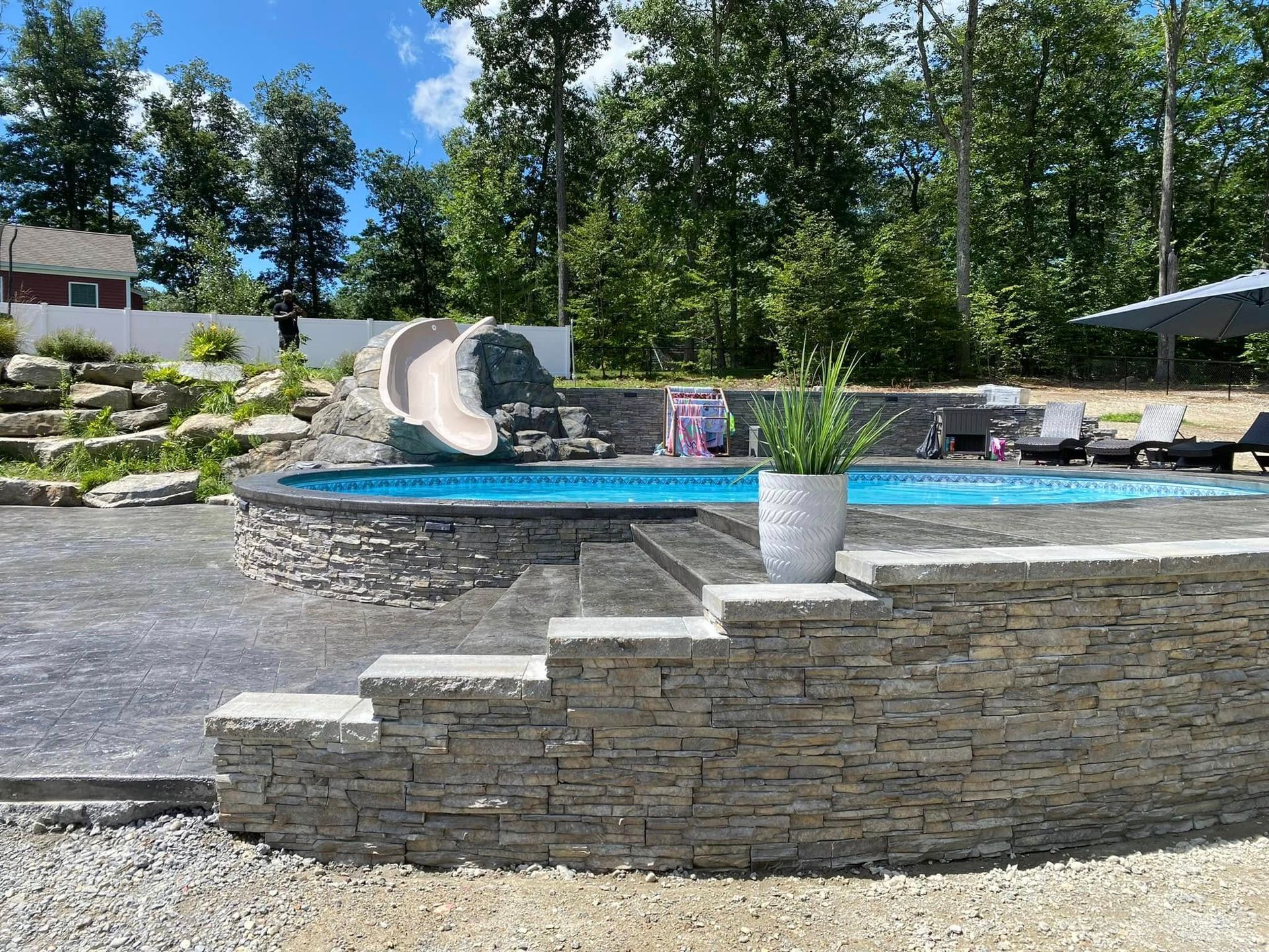 A swimming pool with a water slide and a stone wall surrounding it.