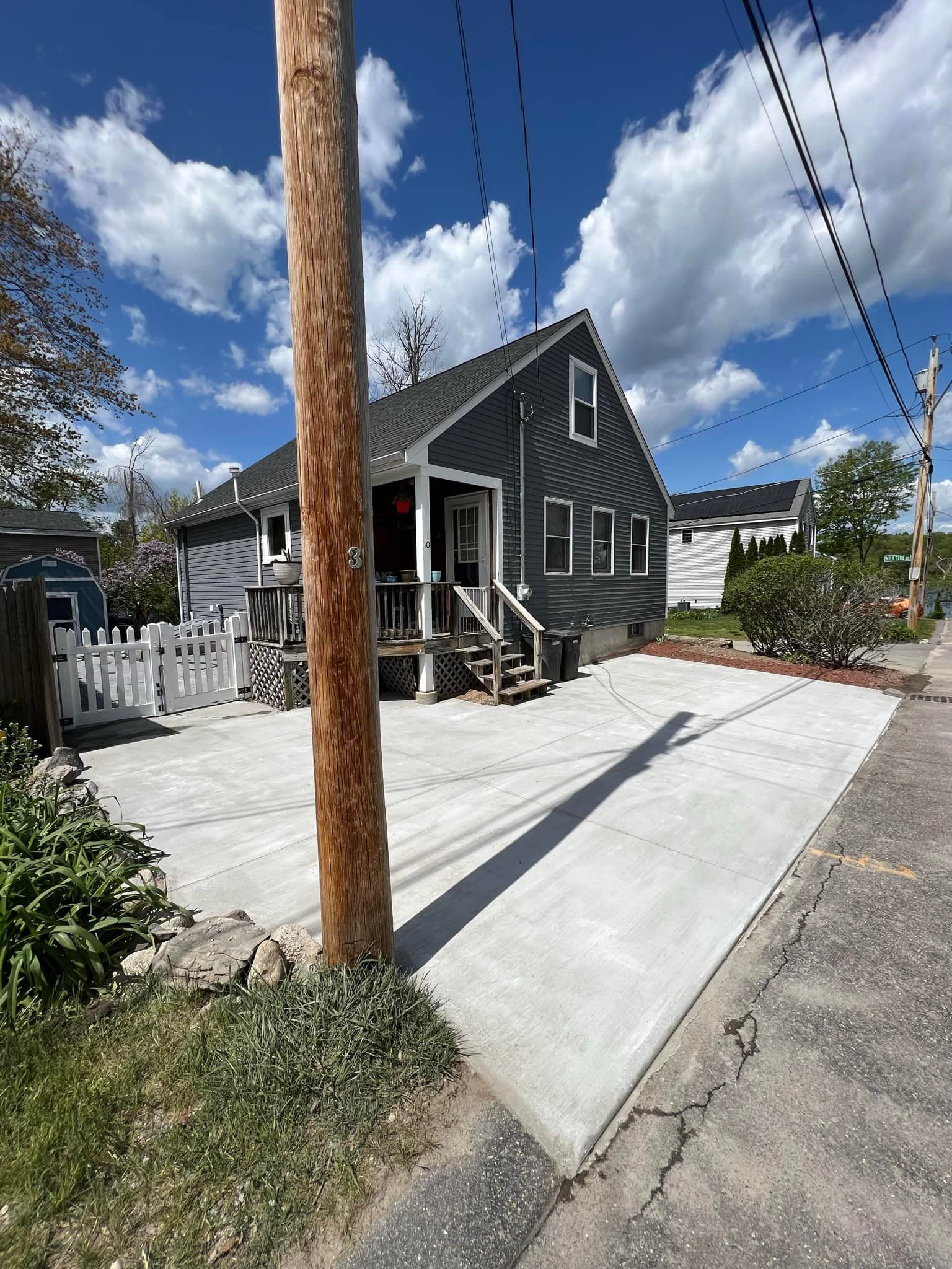 A house with a concrete driveway and a wooden pole in front of it.