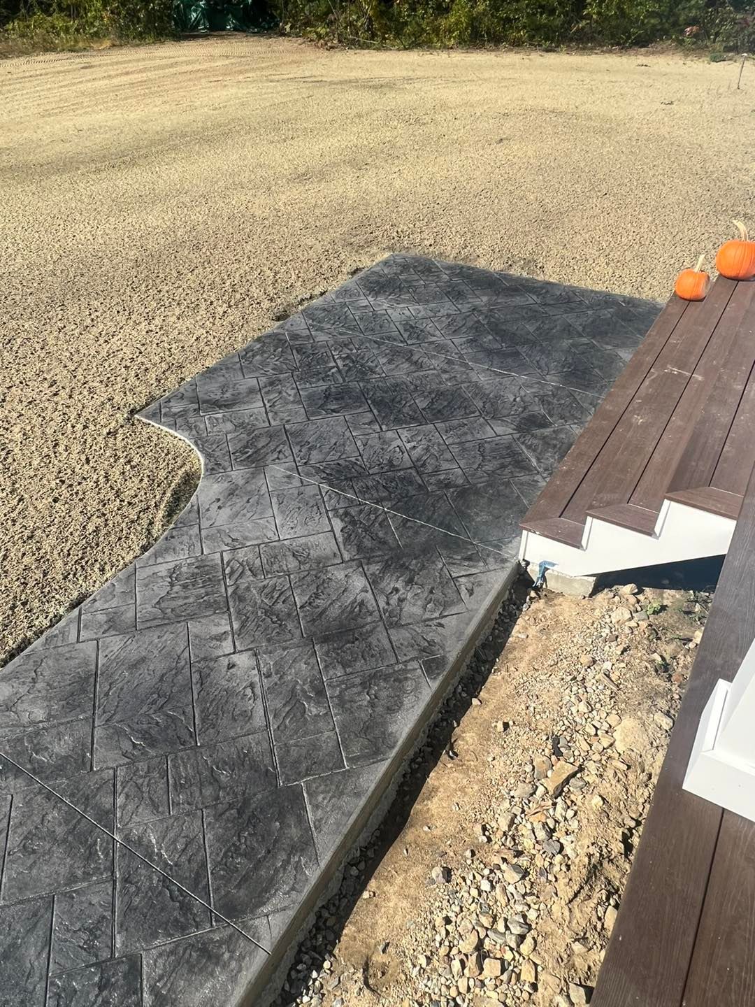 A concrete walkway is being built next to a wooden deck.