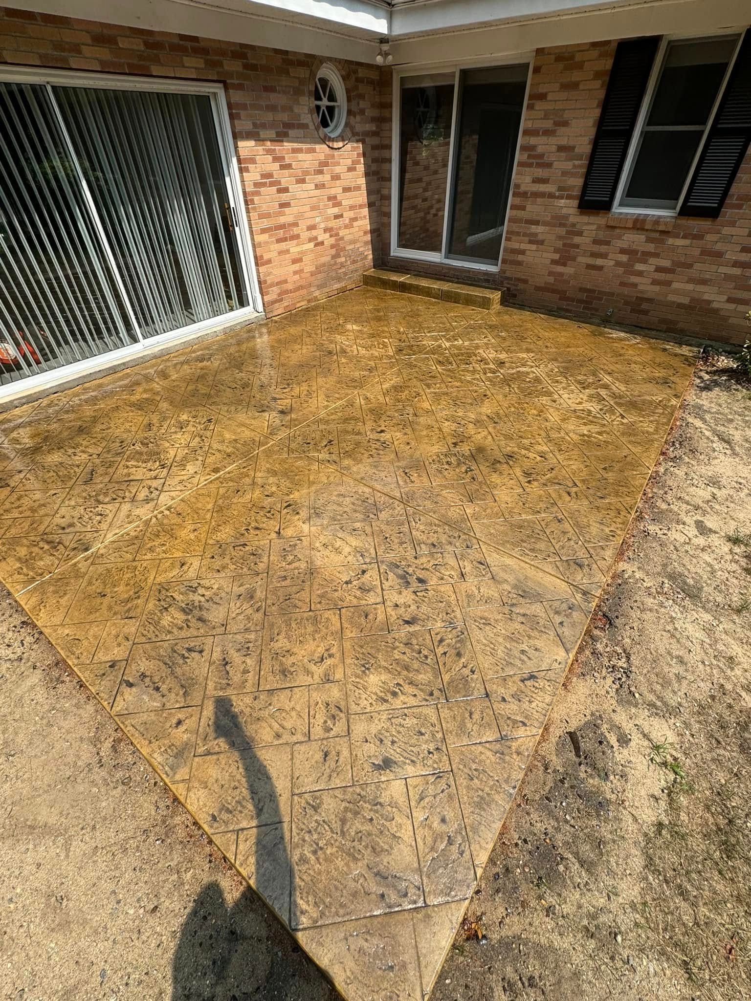 A concrete patio in front of a brick house with a sliding glass door.