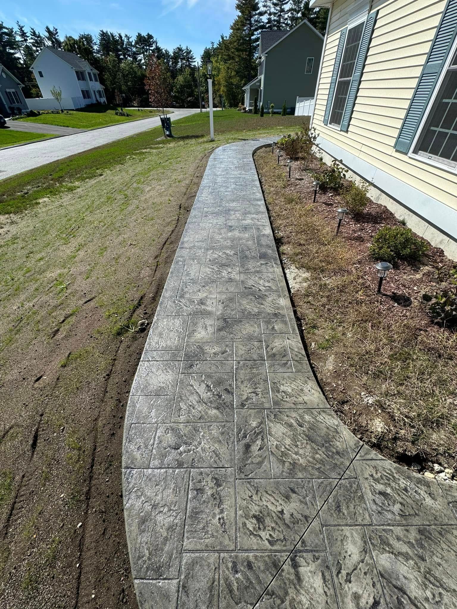A concrete walkway leading to a house in a residential area.