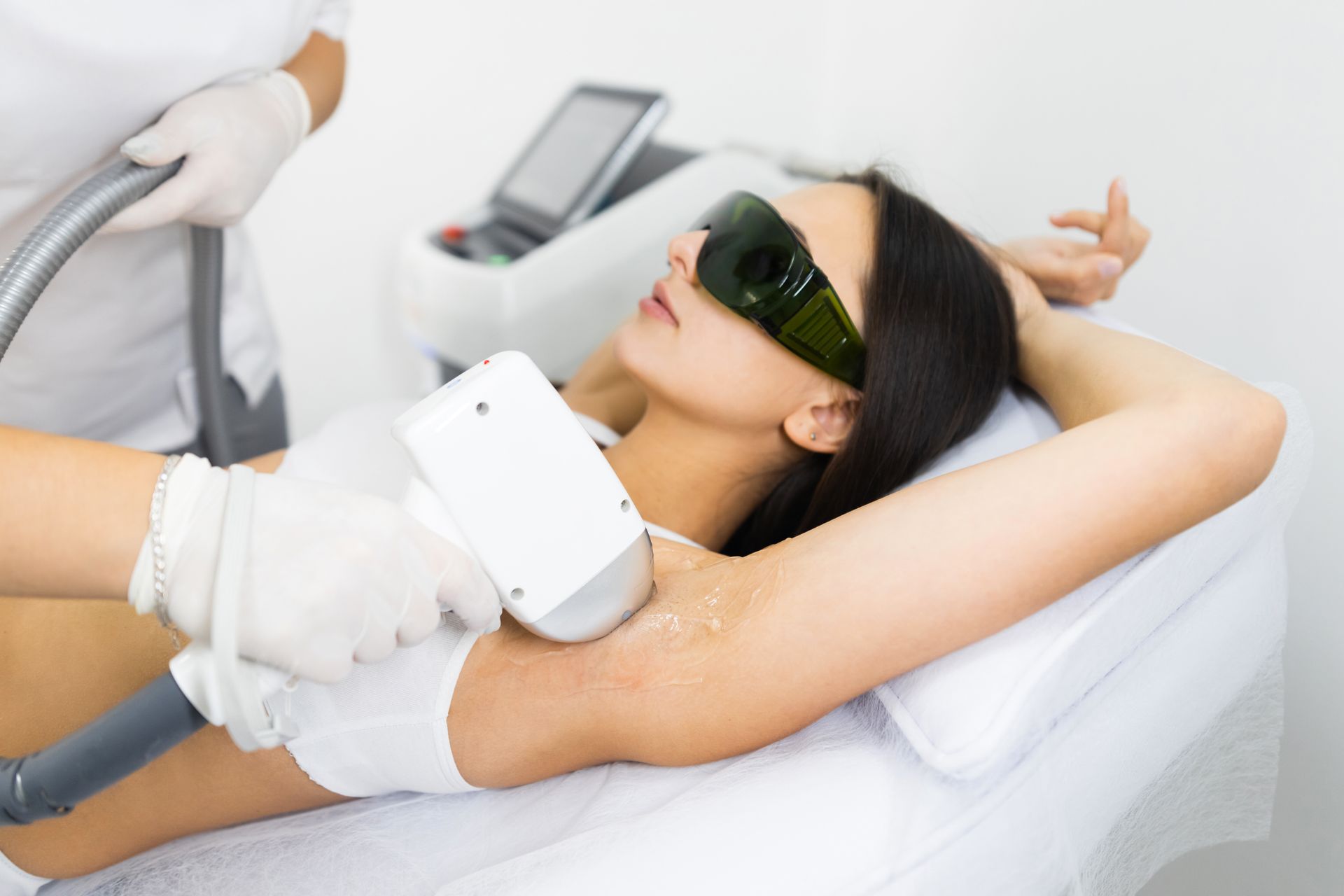 A woman is getting a laser hair removal treatment on her armpit.
