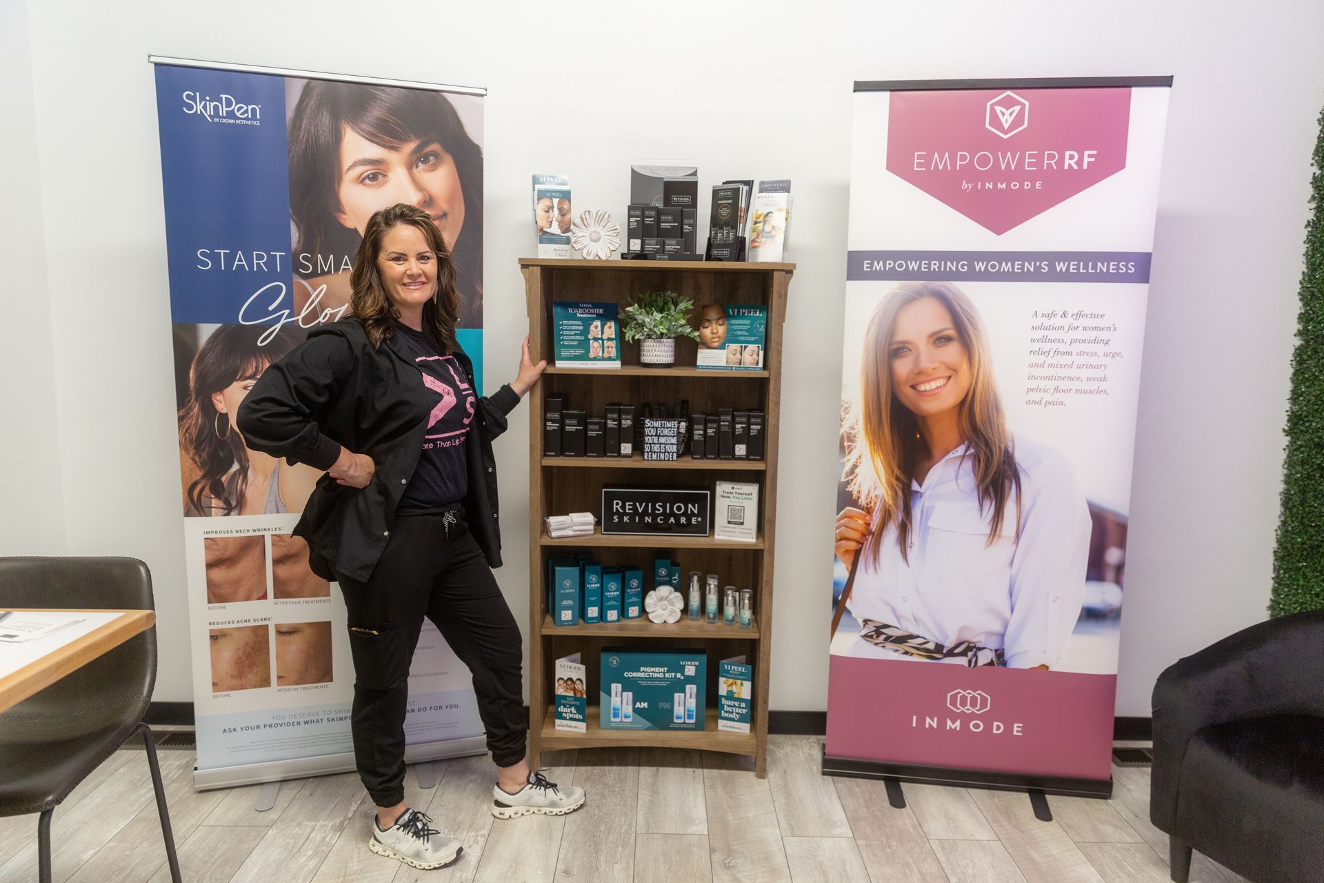 Woman in black sweatsuit poses by a product display shelf, flanked by two promotional banners.