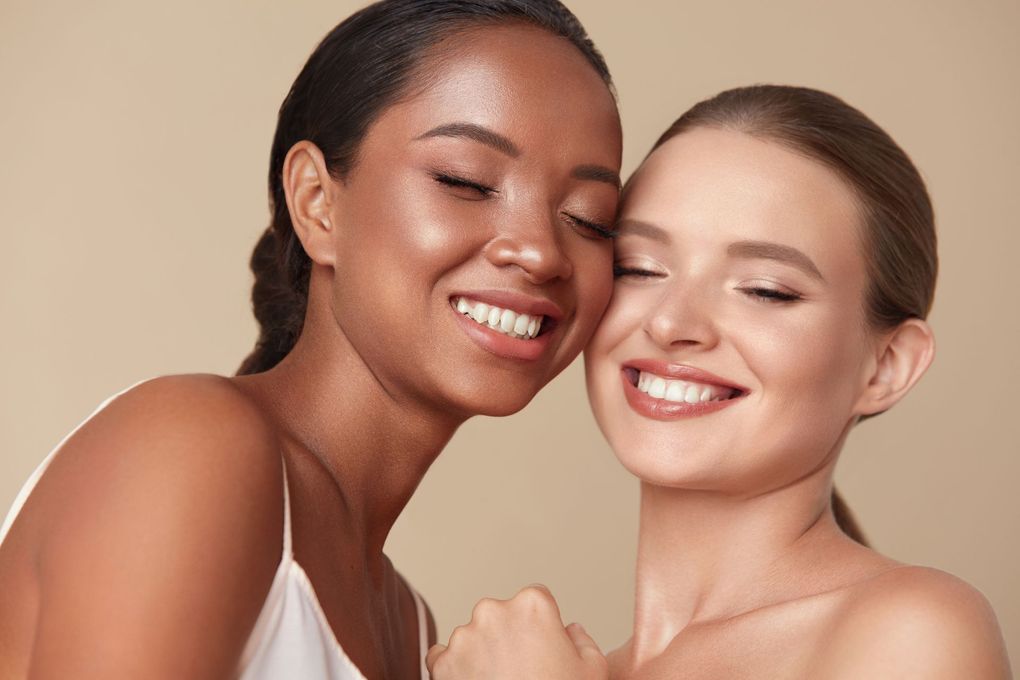 two women are hugging each other and smiling with their eyes closed .