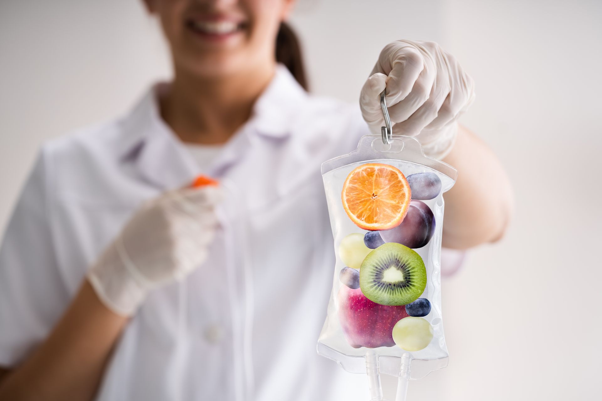 Nurse holding IV bag filled with fruit, smiling.