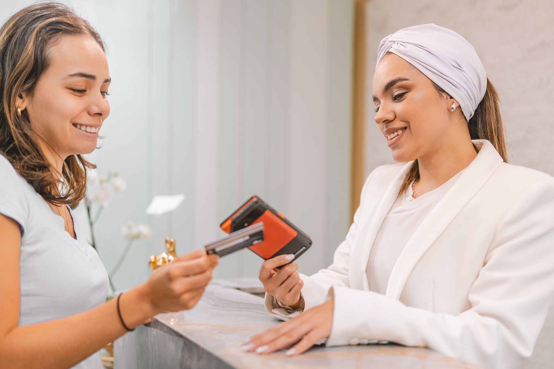 A woman is giving a credit card to another woman at a counter.