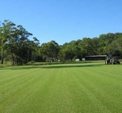 A Tractor Is Plowing A Lush Green Field — Barron River Lawns In Biboohra, QLD