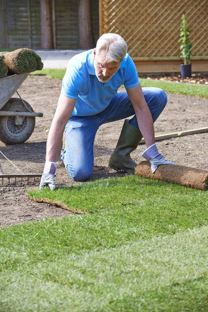 A Man Is Kneeling Down To Roll Out A Roll Of Turf — Barron River Lawns In Mossman, QLD
