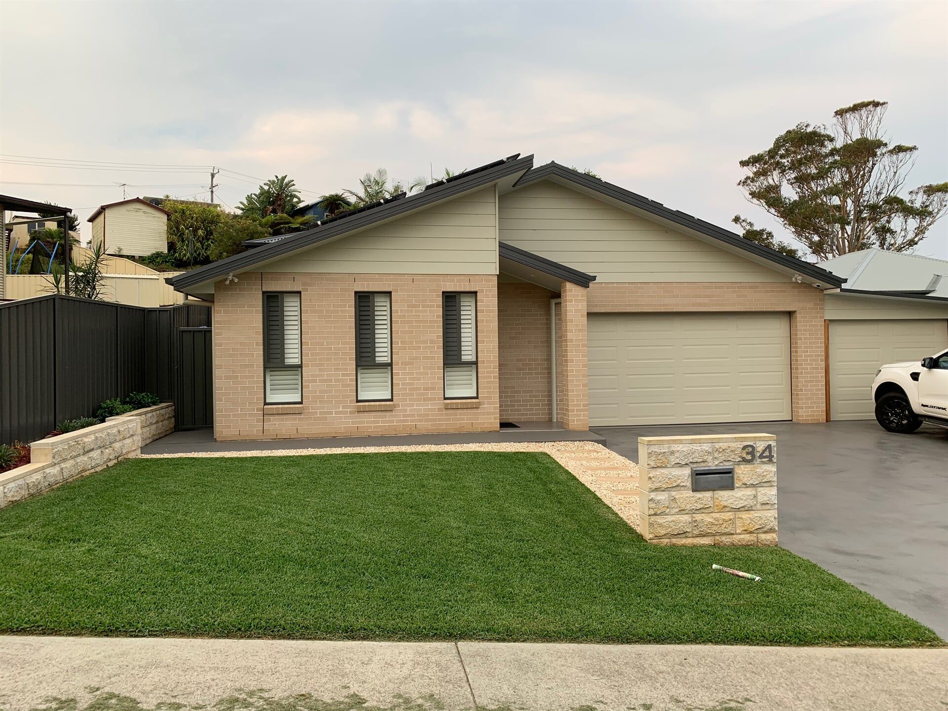 A Man is Standing on a Ladder in Front of a House — Boambee Turf In Bonville, NSW