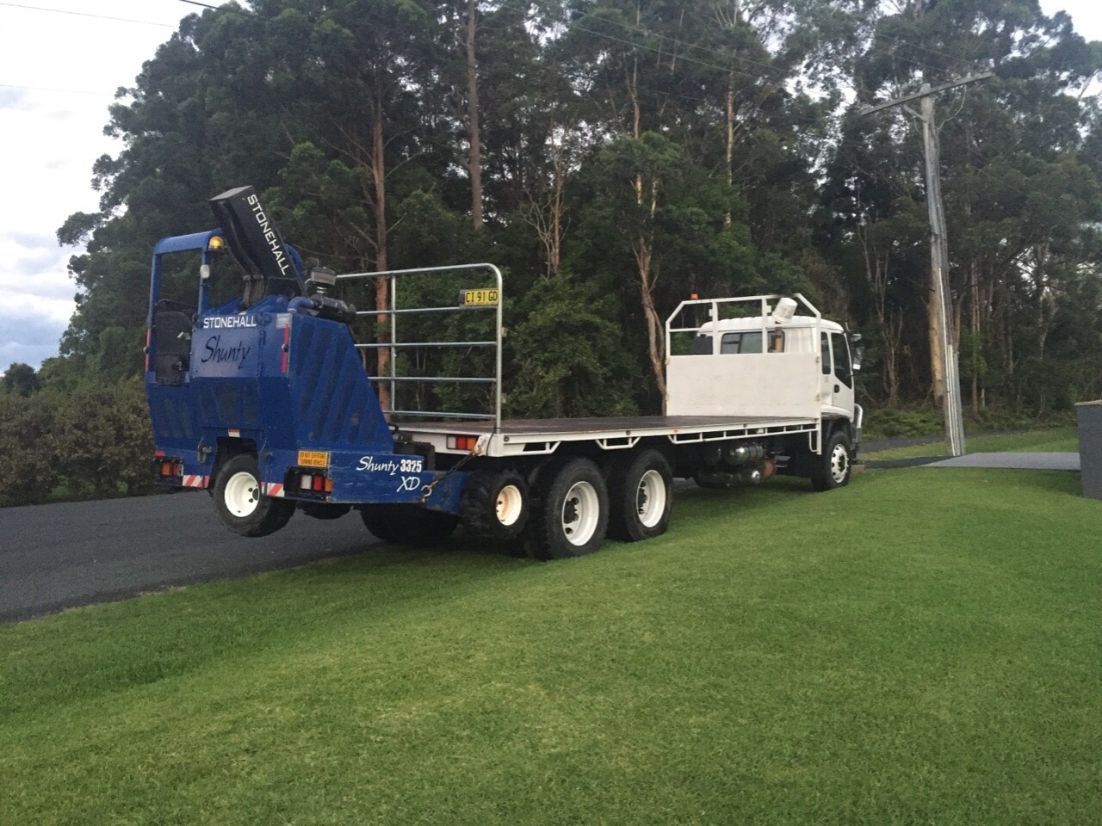 A Blue Truck with a Crane on the back is Parked on the Side of the road — Boambee Turf In Bonville, NSW
