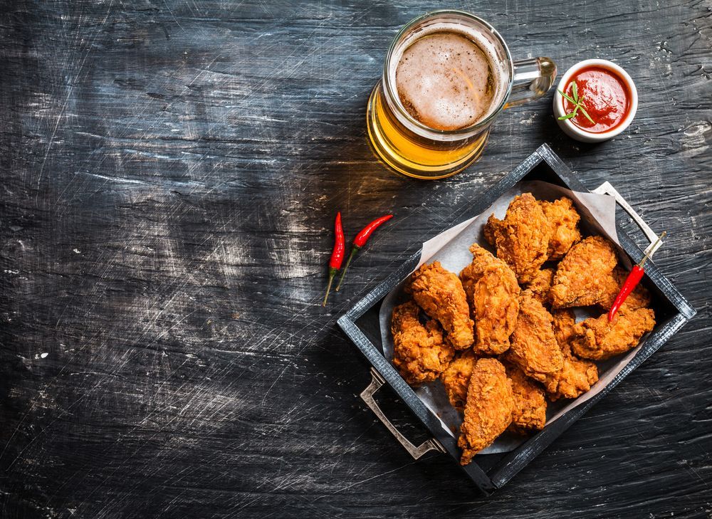 Fried Chicken Wings and a Glass of Beer on a Wooden Table — Capricorn Tavern in Taranganba, QLD