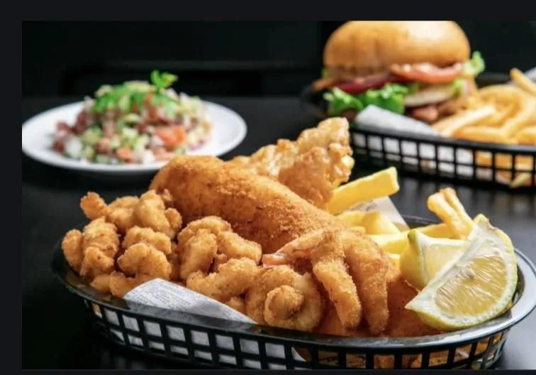 A Basket of Fried Shrimp and French Fries on a Table Next to a Plate of Food — Capricorn Tavern in Taranganba, QLD