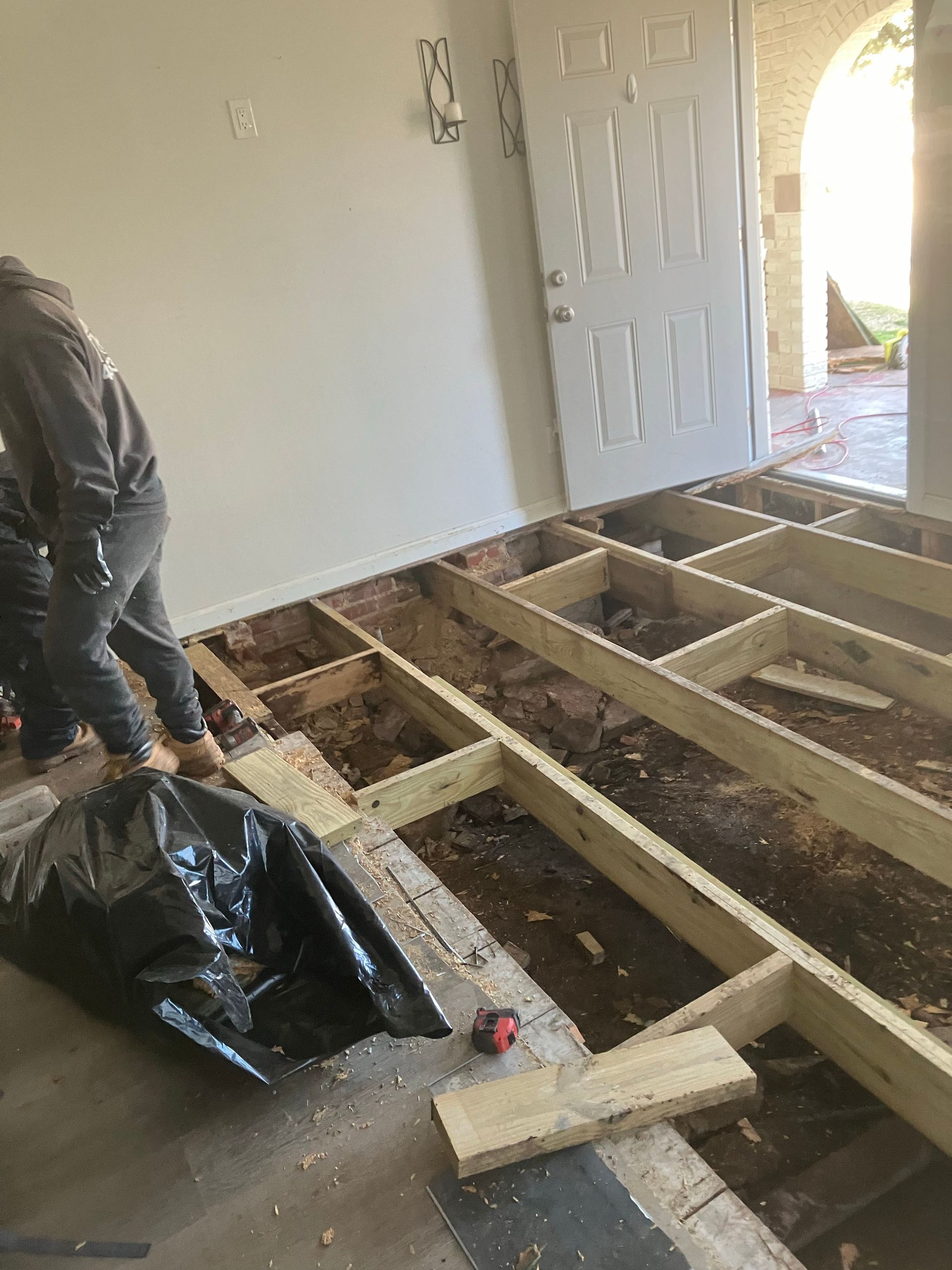 A man is working on a wooden floor in a living room.