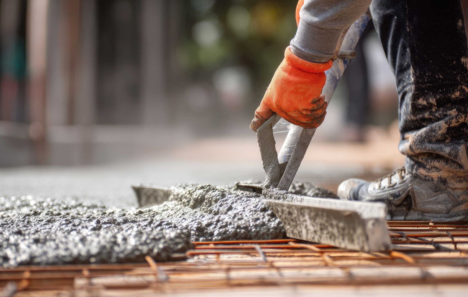 A worker using a hand tool to level wet cement during a professional concrete repair job.