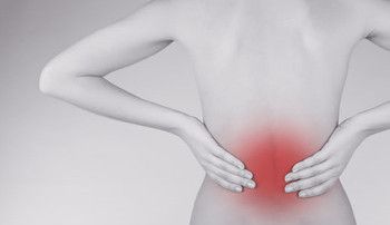 A lady's hands on her lower back, where the painful area is shown in red