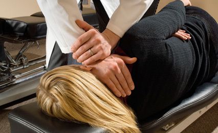A lady lying on her side with therapist's hands on her neck and shoulder