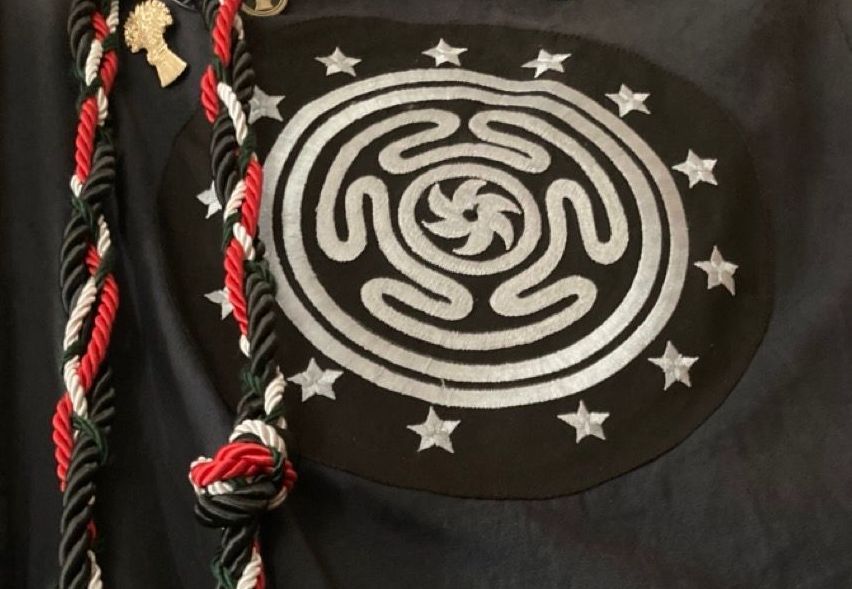 A black cloth with a woven cord and a black and white symbol, Hecate's wheel.