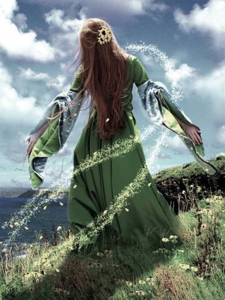 a woman in a green dress is standing in a field surrounded by magic.