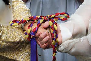 Couple clasping hands during a Wiccan handfasting ceremony.