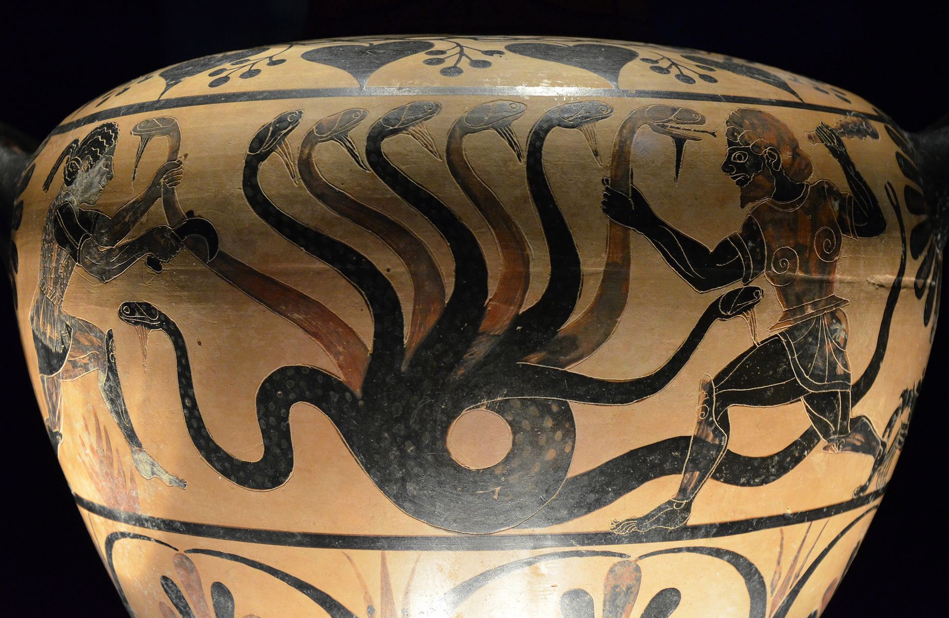 A Greek vase with a snake and a man on it.