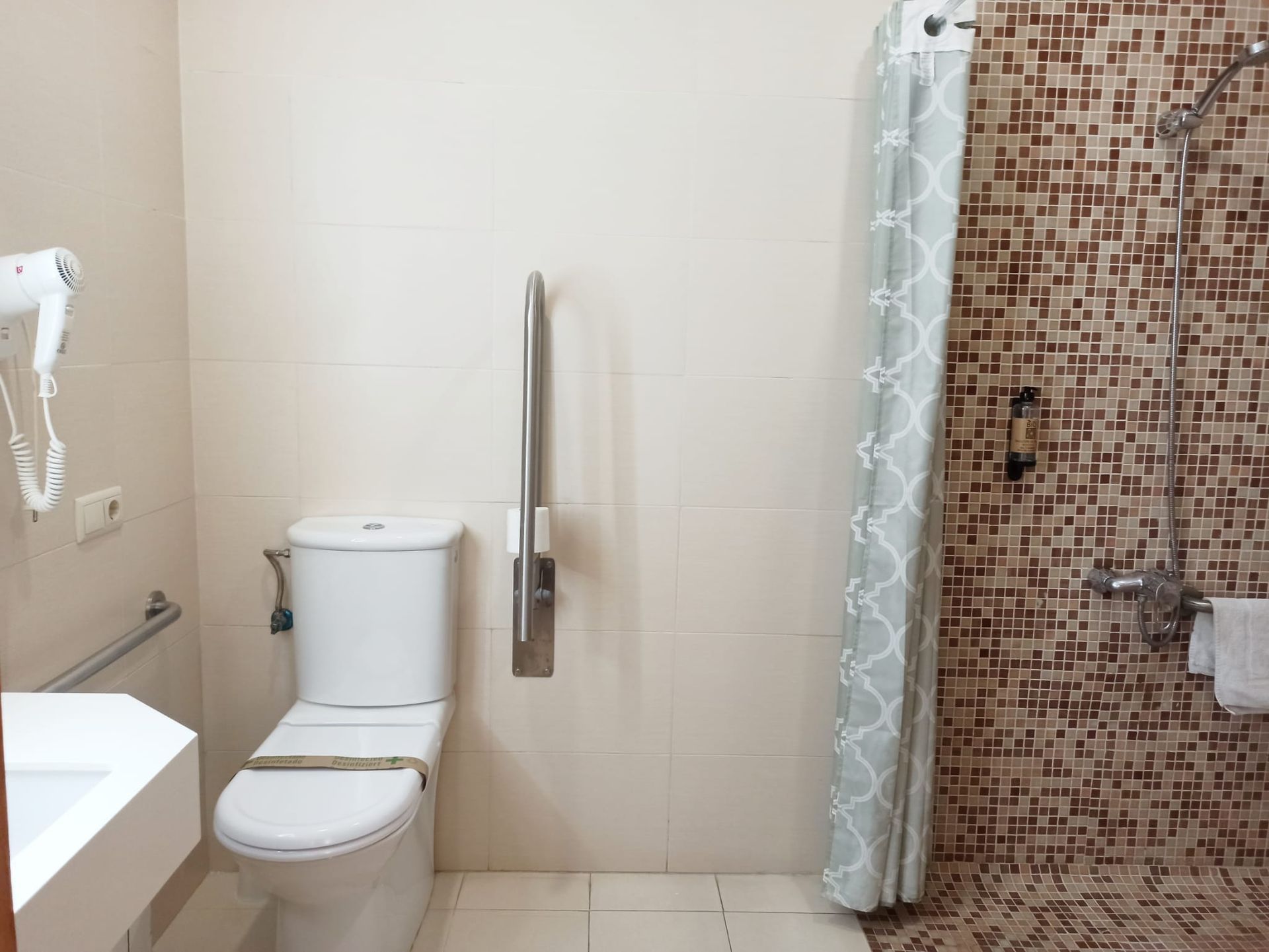 A bathroom with a toilet , sink and shower.