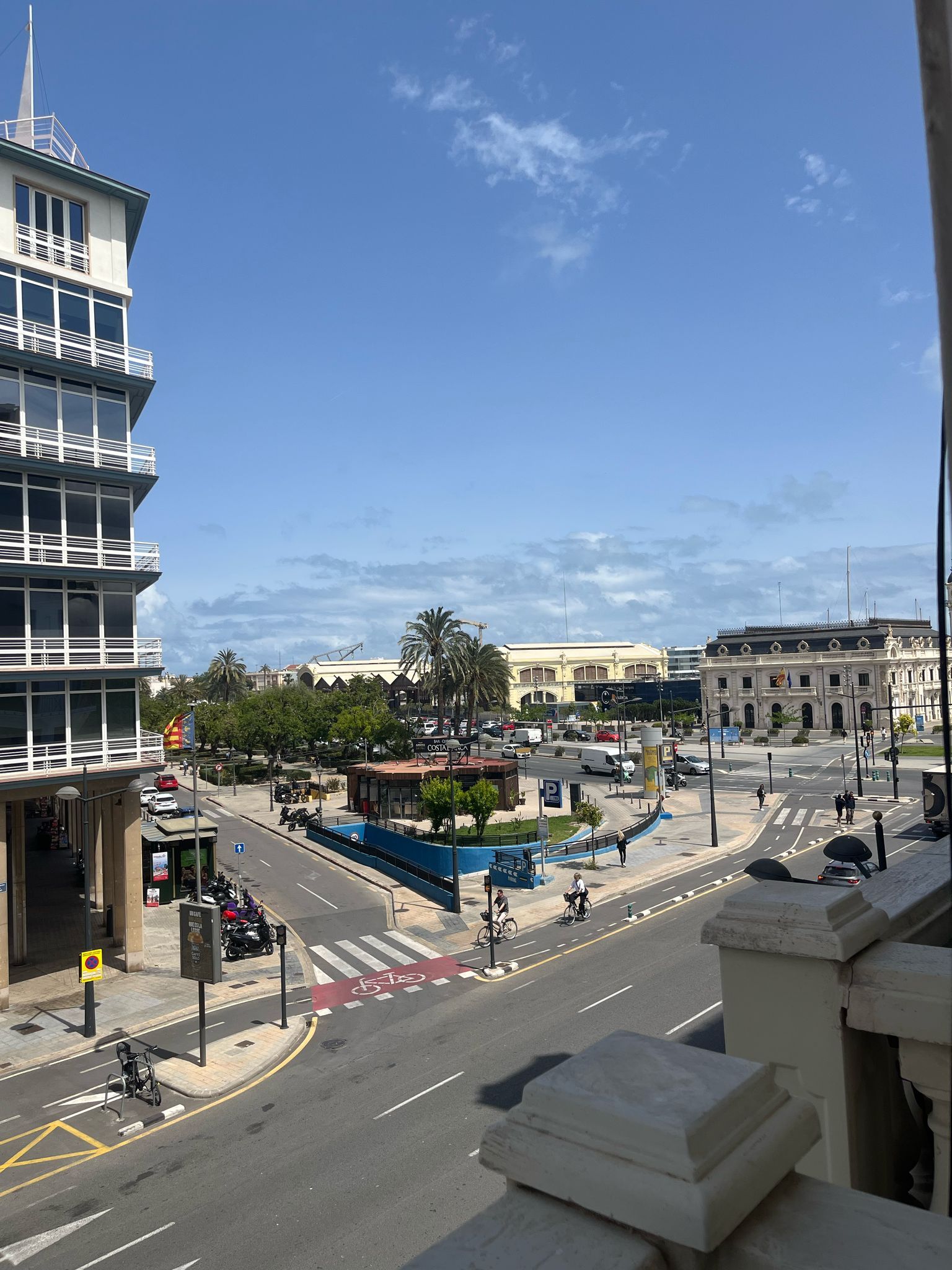 A view of a city street from a balcony on a sunny day
