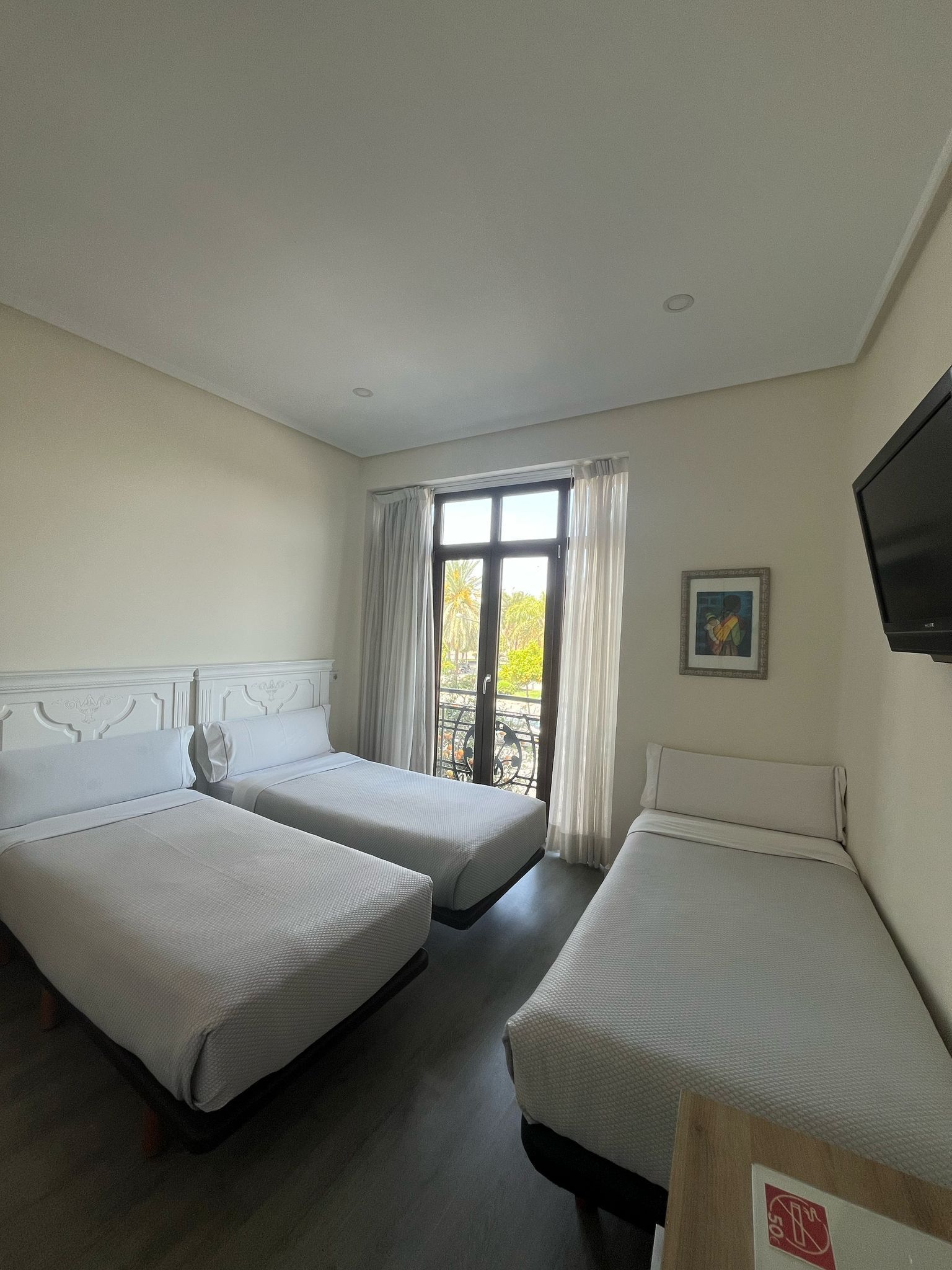 A hotel room with three beds and a television.