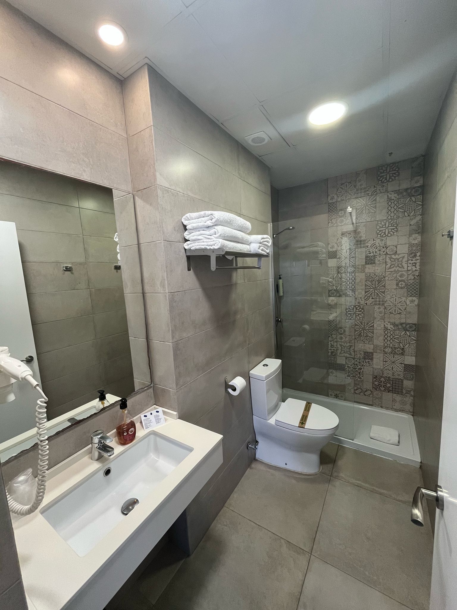 A bathroom with a sink , toilet , shower and mirror.