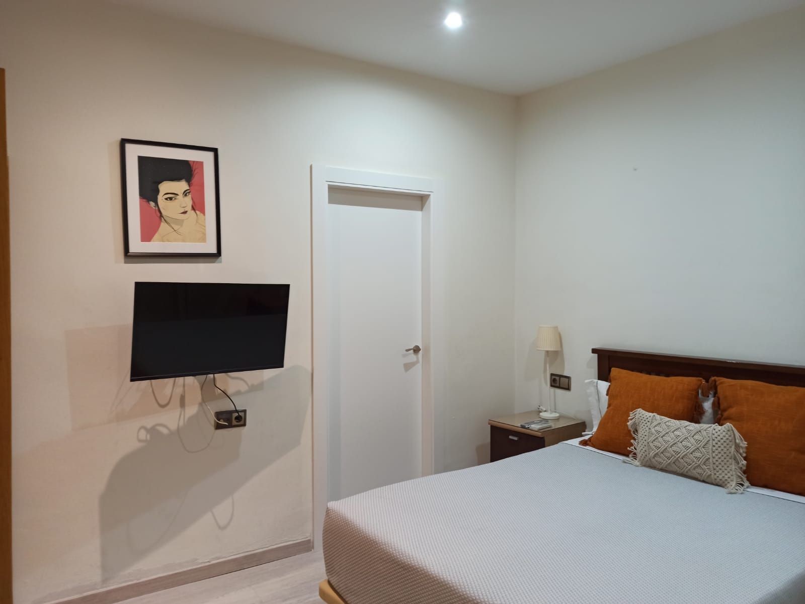 A bedroom with a bed , television and a picture on the wall.