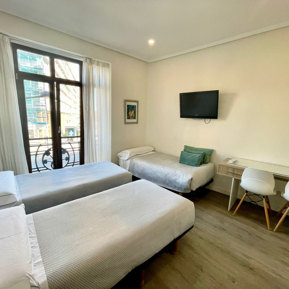 A hotel room with two beds , a desk and a television.