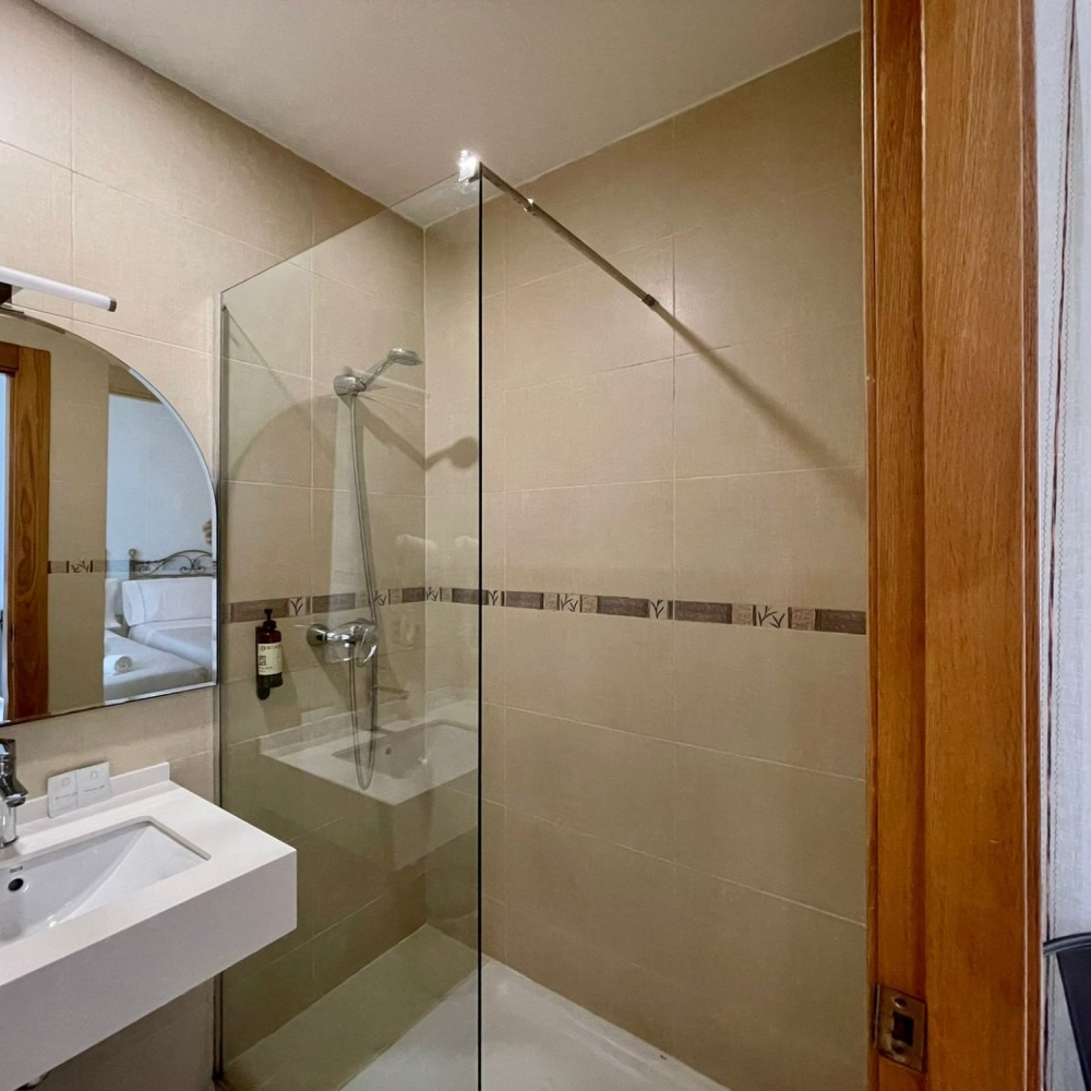 A bathroom with a walk in shower and a sink