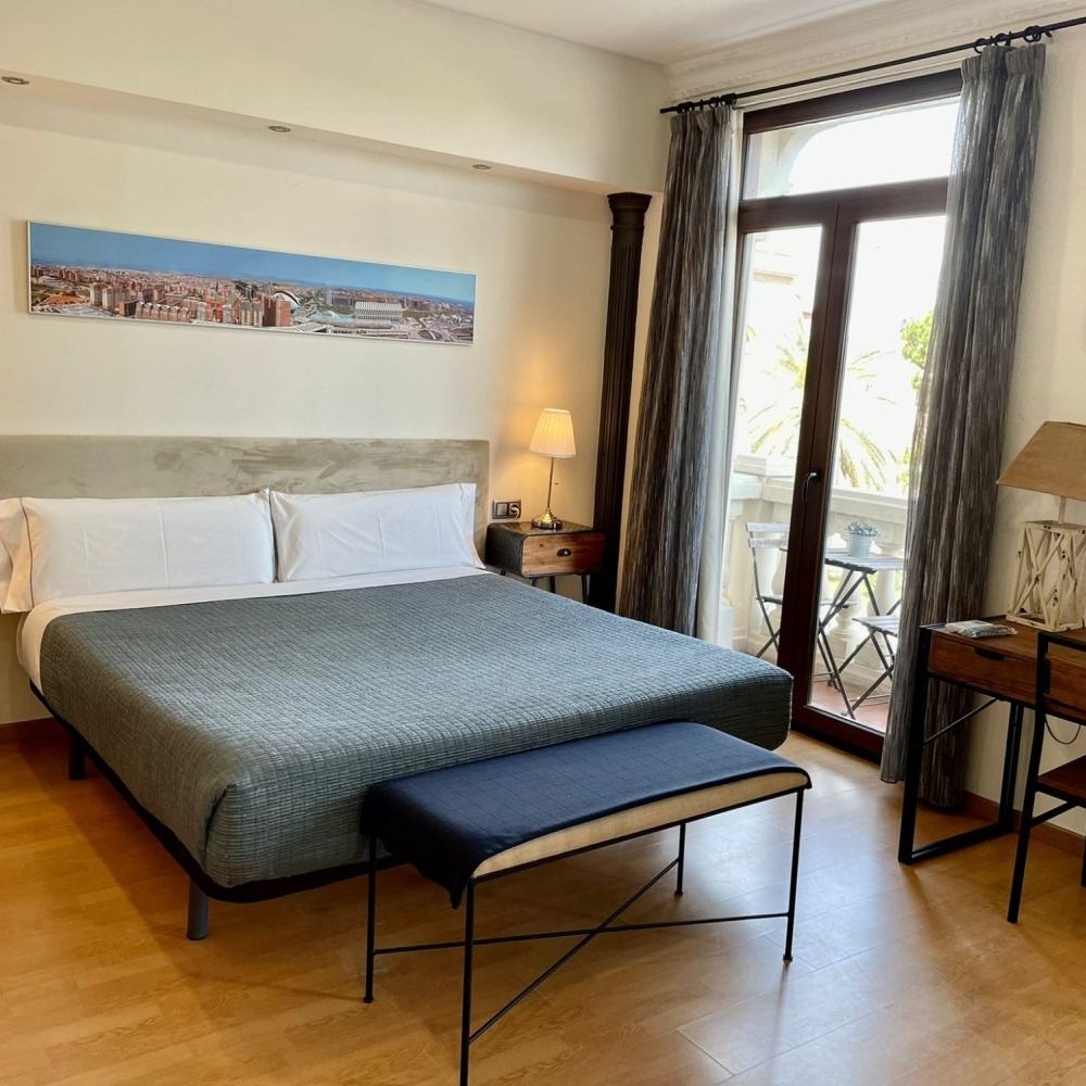 A hotel room with a large bed and a bench