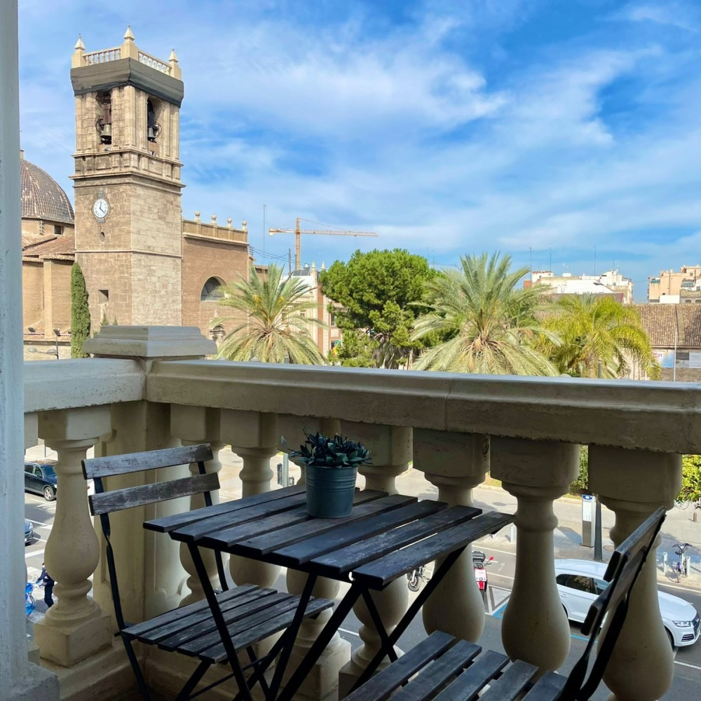 A balcony with a table and chairs and a clock tower in the background